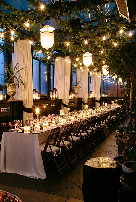 an indoor dining area with tables and chairs covered in white tablecloths, lit by hanging lights