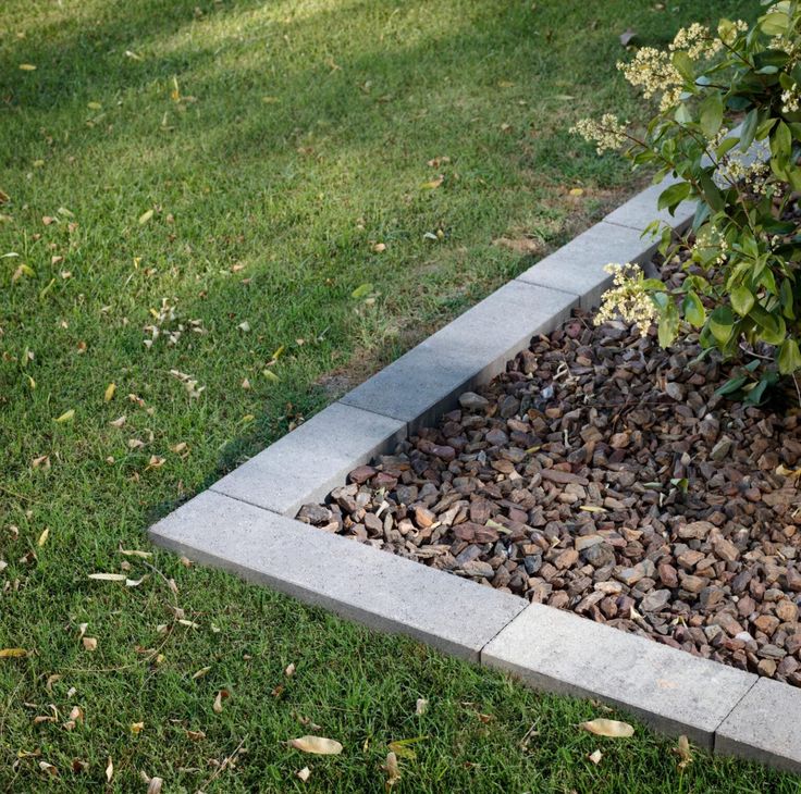 a planter filled with rocks sitting on top of a lush green field next to a tree