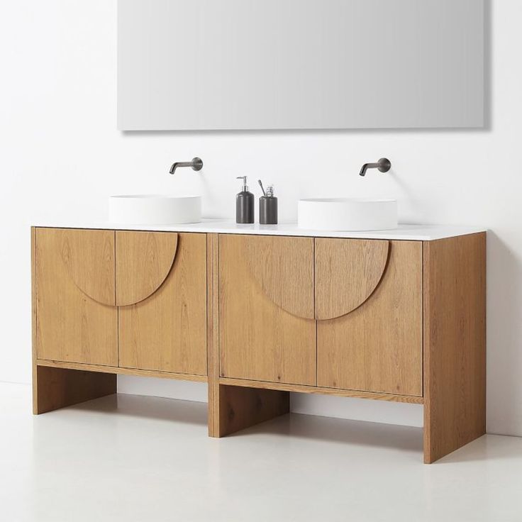 two white sinks sitting on top of a wooden cabinet next to a wall mounted mirror