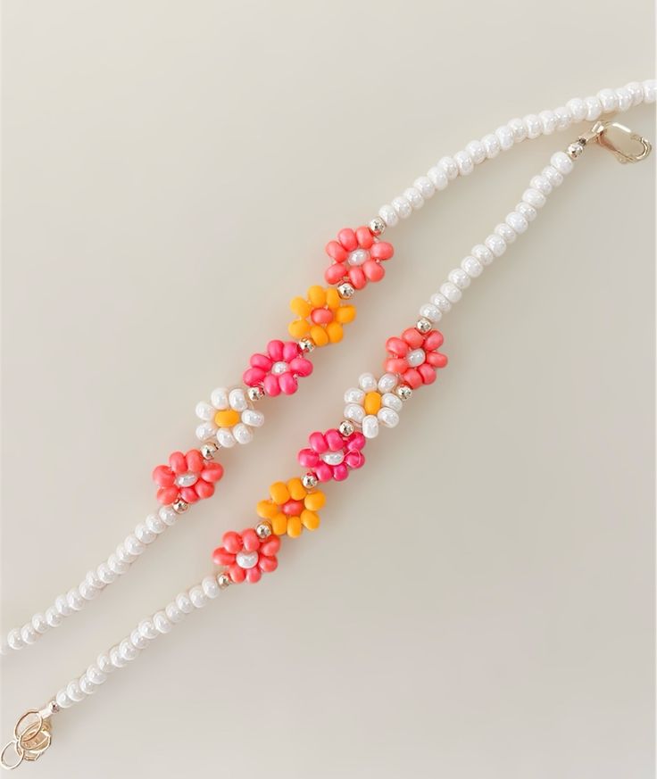 two necklaces with beads and flowers on them, one has a white beaded cord