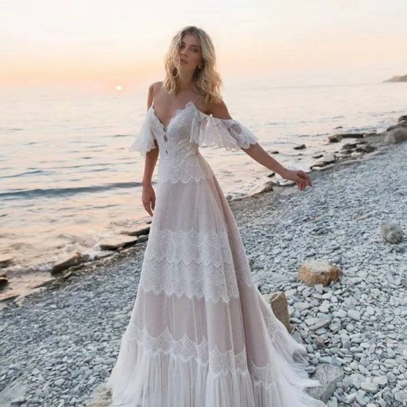 a woman standing on top of a beach next to the ocean wearing a white dress