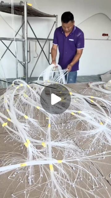 a man in purple shirt standing next to a pile of white wires