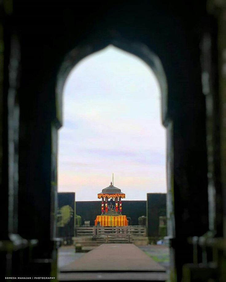 an archway leading to a small building with a clock tower in the backgroud