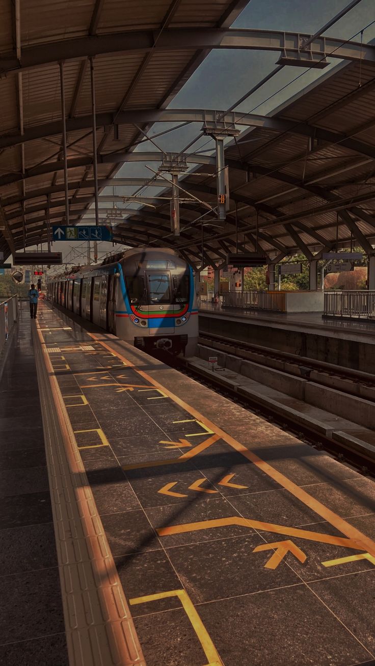 a train pulling into a station with people waiting on the platform for it to arrive