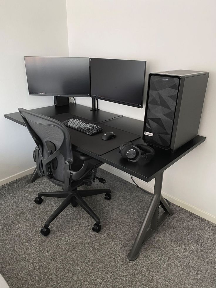 two computer monitors sitting on top of a black desk