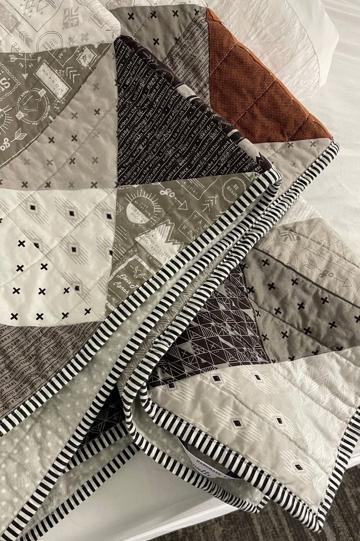 a pile of quilts sitting on top of a bed next to a white pillow