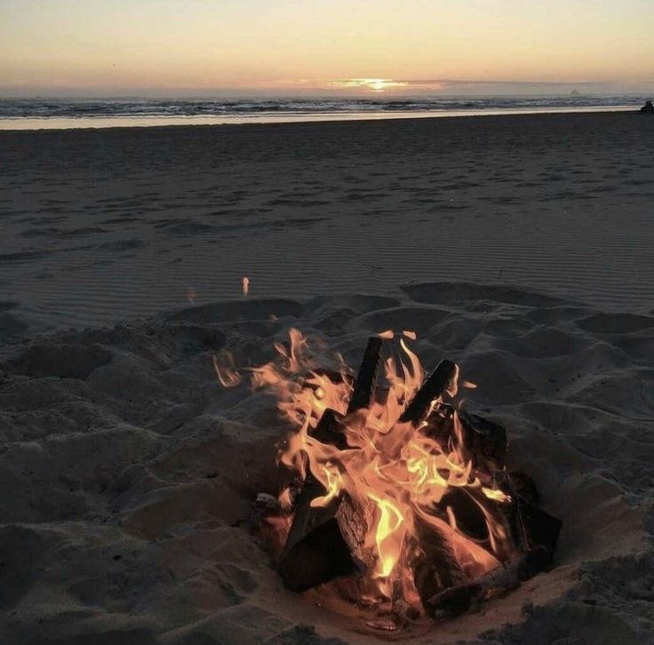 a fire pit on the beach at sunset