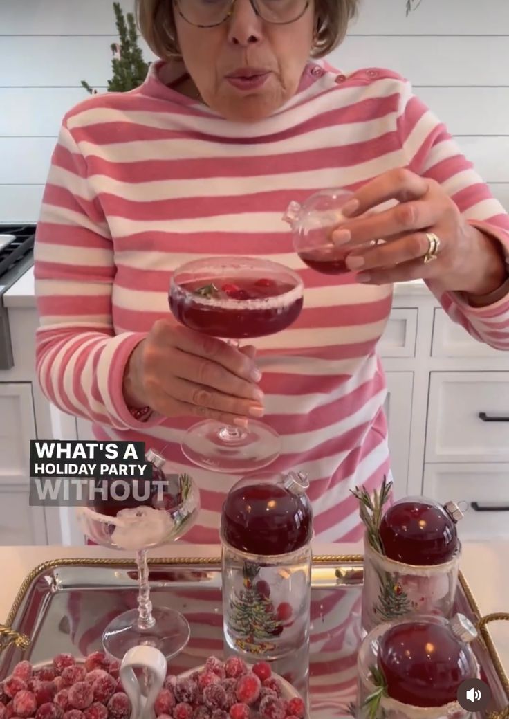 an older woman holding a wine glass in front of some desserts on a tray