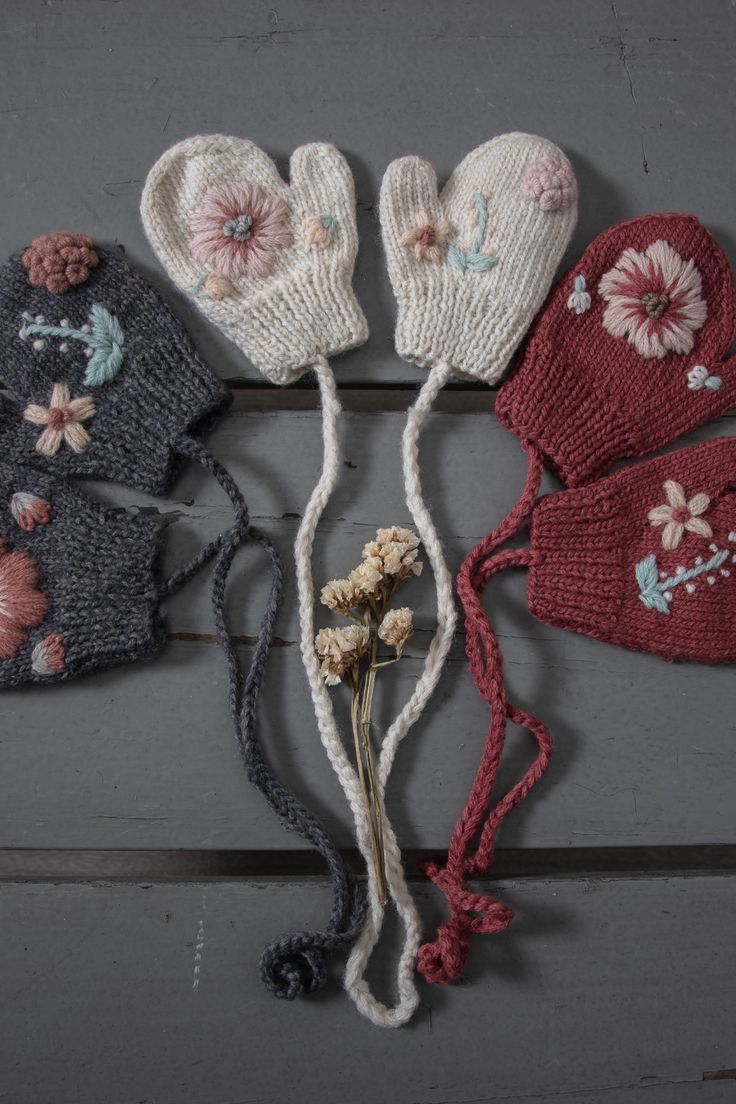 four knitted mittens with flowers on them