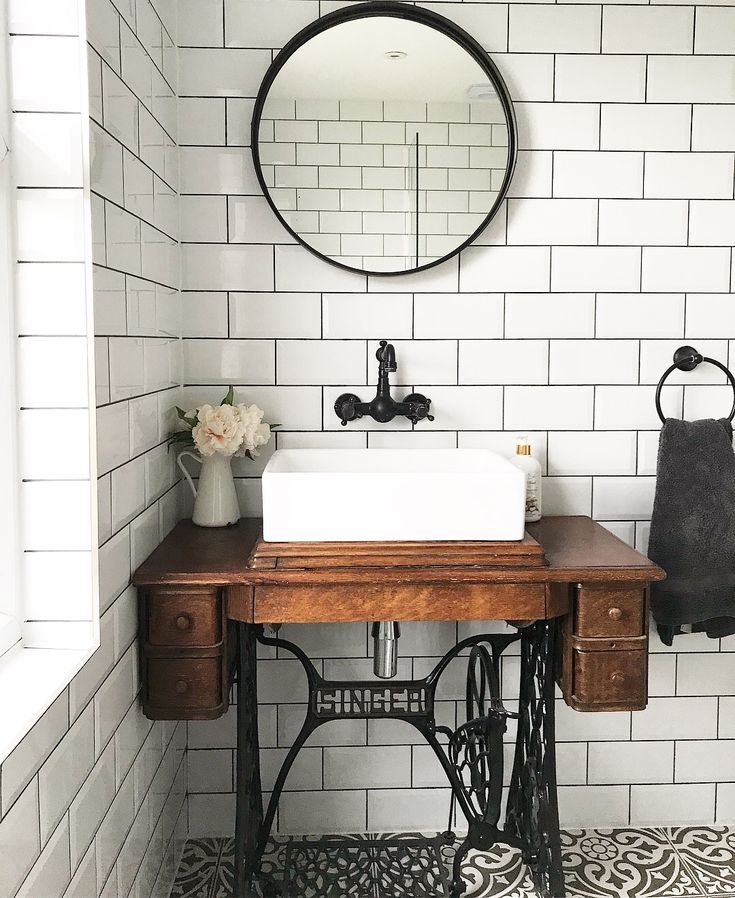 a bathroom with a sink, mirror and sewing machine on the table in front of it