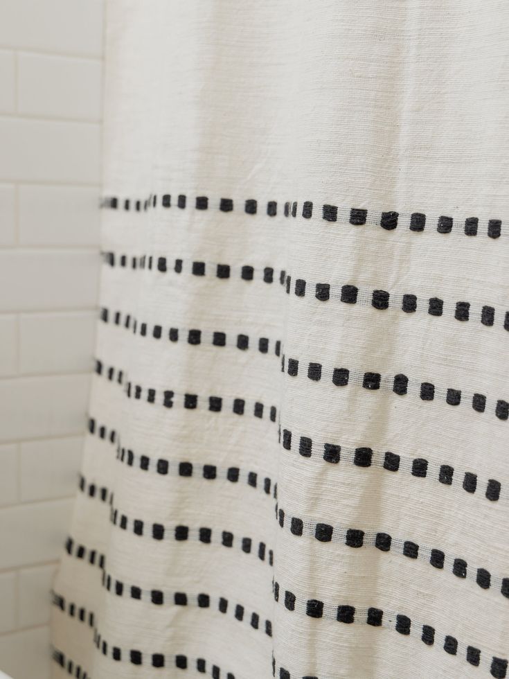 a white shower curtain with black dots on it