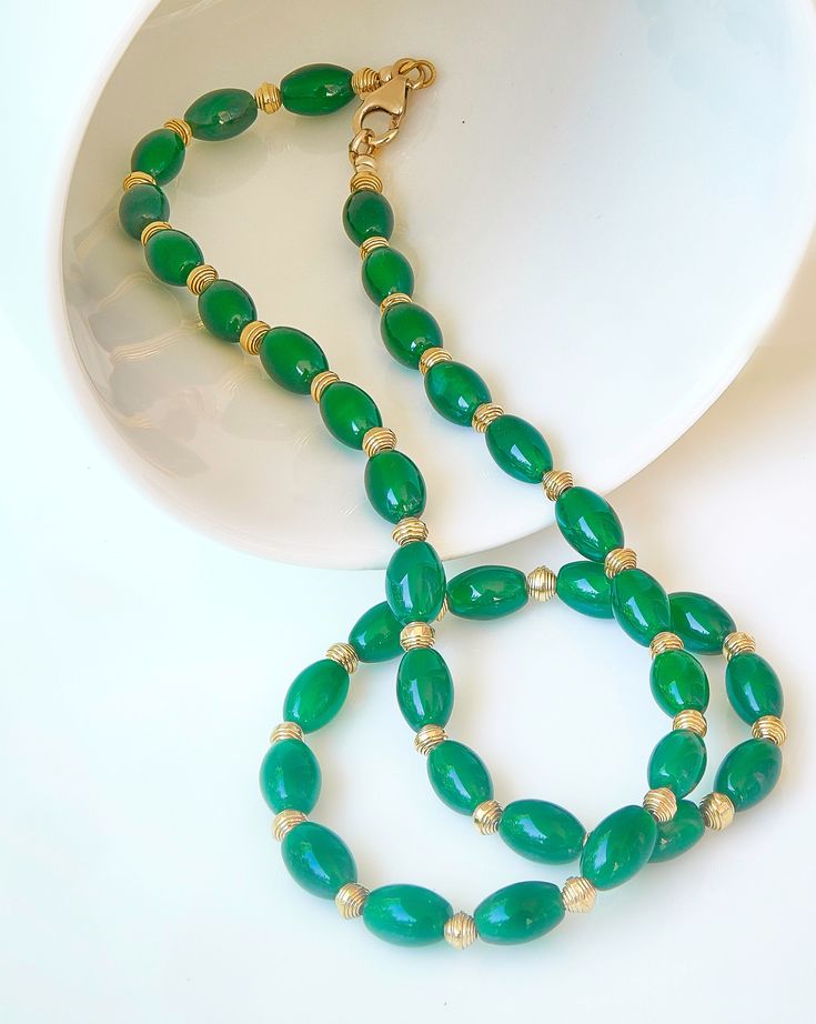 Elegant beaded necklace made with green onyx barrel beads (6x9mm) and 24k gold vermeil curled ribbon spacer beads (4x3.5mm). The single strand necklace is 18 inches long and closes with a 14k gold filled lobster claw clasp. Please message me if you would prefer a gold filled toggle clasp instead. I use only the best beading wire available for maximum flexibility and strength and crimp the ends for extra security. See more of my necklace designs at https://www.etsy.com/shop/JenniferMarcusDesign?ref=profile_header Elegant Green Onyx Beaded Necklaces, Elegant Gold Beaded Necklaces With Green Onyx, Elegant Gold Beaded Necklace With Green Onyx, Gold Jade Necklaces With Polished Beads, Elegant Green Oval Bead Necklaces, Elegant Green Necklaces With Oval Beads, Elegant Green Oval Beaded Necklaces, Gold Emerald Necklace With Round Beads Single Strand, Gold Emerald Necklace With Round Beads