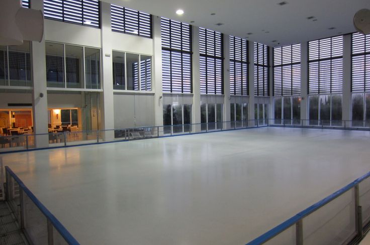 an indoor skating rink with large windows in the background