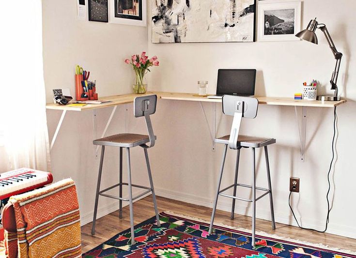 two stools sit in front of a desk with a computer on it and pictures above