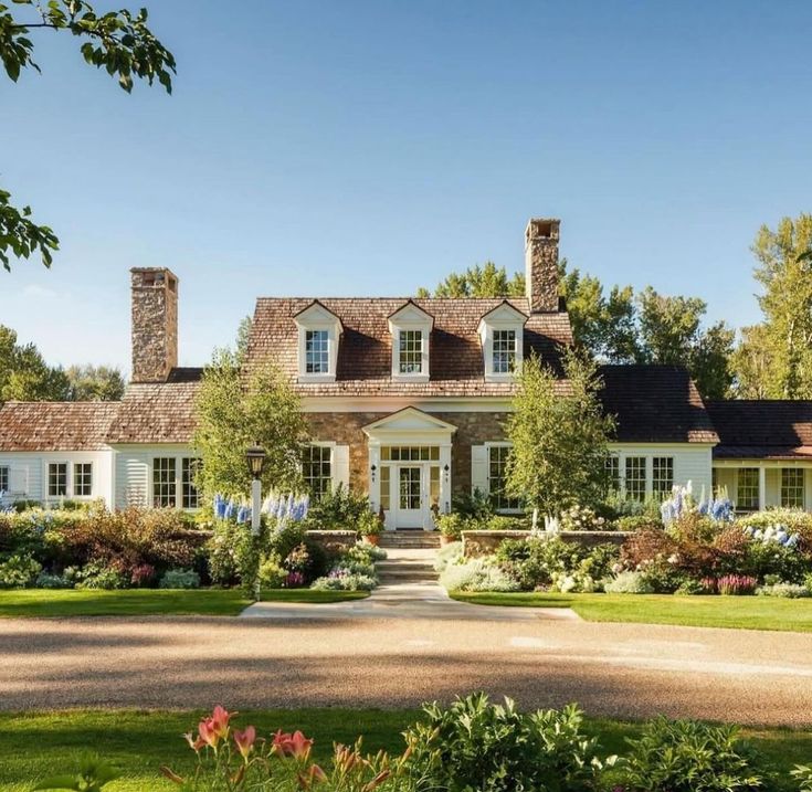 a large white house surrounded by trees and flowers