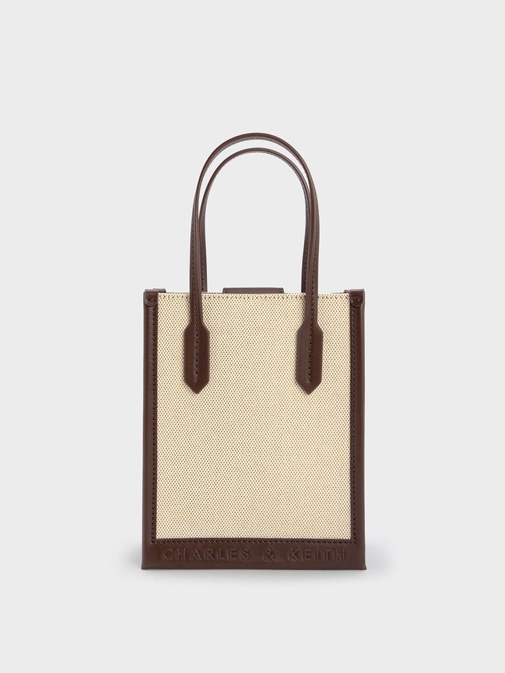 Cool and utterly chic, this geometric canvas tote bag is the perfect piece to complete any casual ensemble. Featuring a classic rectangular silhouette, a versatile cream-and-brown colourway, and lightweight canvas construction, this bag will slot seamlessly into your wardrobe rotation. Carry yours by the elongated double handles, or simply clip on the detachable strap and turn it into a crossbody bag for hands-free convenience. Rectangular Brown Box Bag In Coated Canvas, Beige Double Handle Box Bag With Dust Bag, Chic Coated Canvas Box Bag With Dust Bag, Square Brown Coated Canvas Bag, Brown Square Coated Canvas Bag, Beige Top Handle Box Bag For On-the-go, Rectangular Coated Canvas Box Bag, Rectangular Box Bag With Leather Handles For Shopping, Beige Satchel For Shopping With Dust Bag