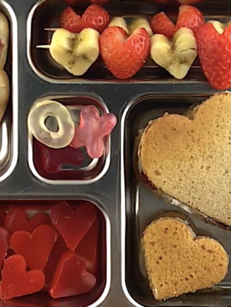 an assortment of heart shaped foods in trays with hearts and apples on the side