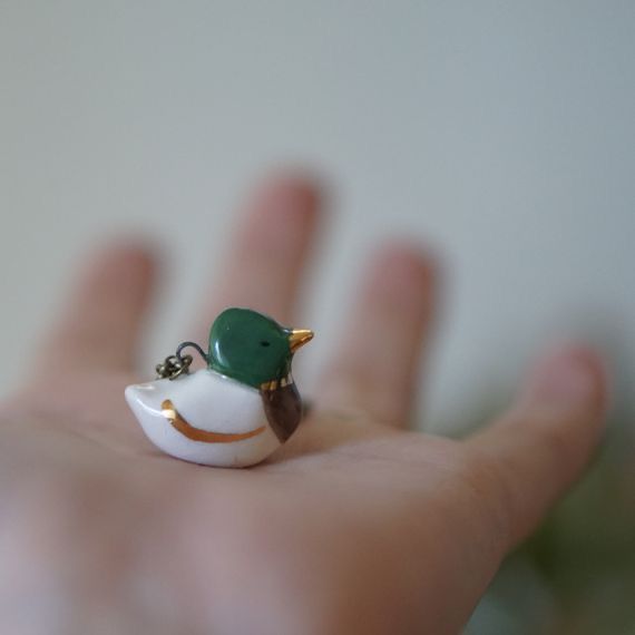 a tiny toy bird sitting on top of a person's hand