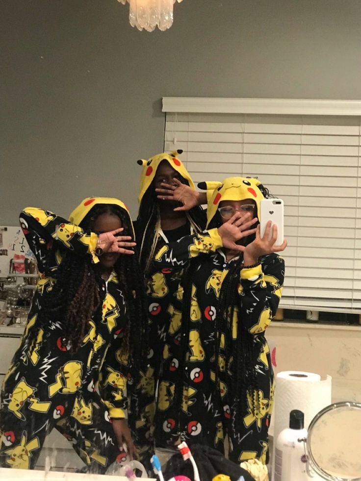 three people dressed in yellow and black are posing for the camera with their arms around each other