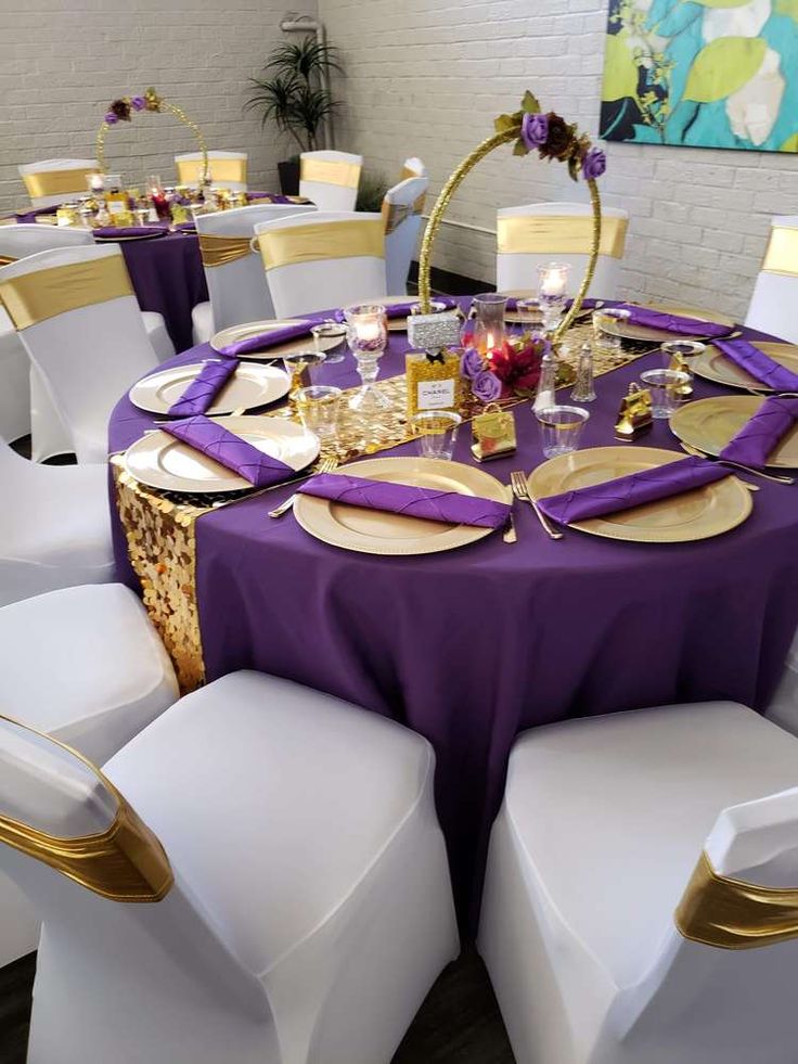 the table is set with white chairs and purple linens for an elegant dinner party