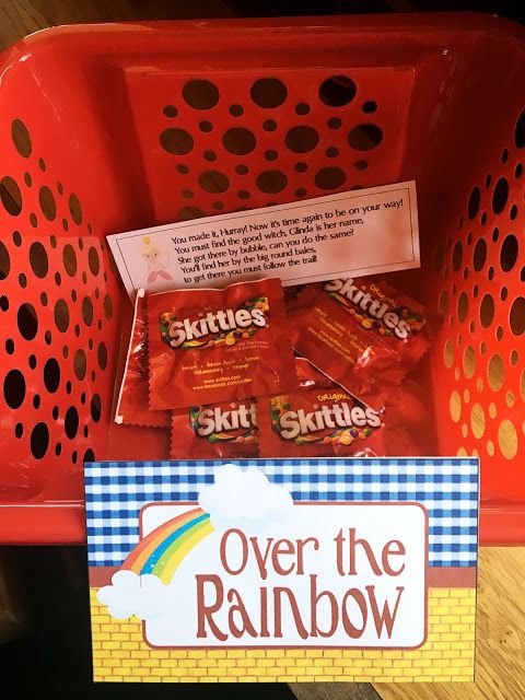 over the rainbow candy bar in a red plastic basket on a wooden table next to a sign that says skittles