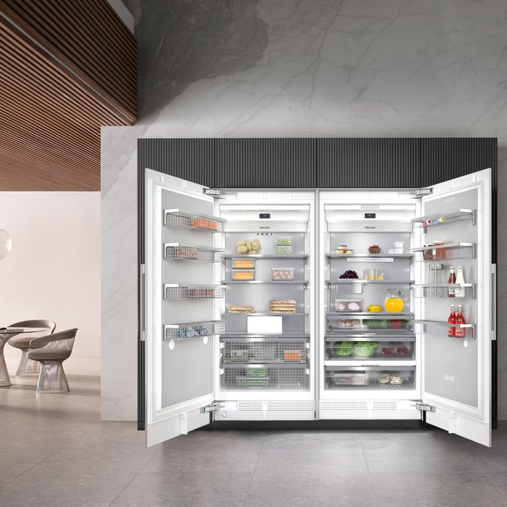 an open refrigerator with its doors wide open in a room that has tables and chairs around it