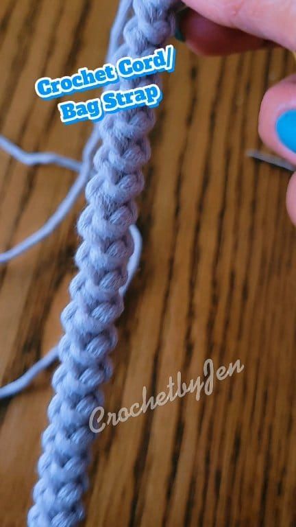 crochet cord bag strap being worked on by someone using the hook to attach it