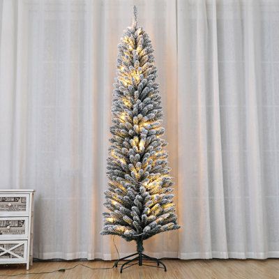 a white christmas tree with gold lights in front of a curtained wall and wooden floor