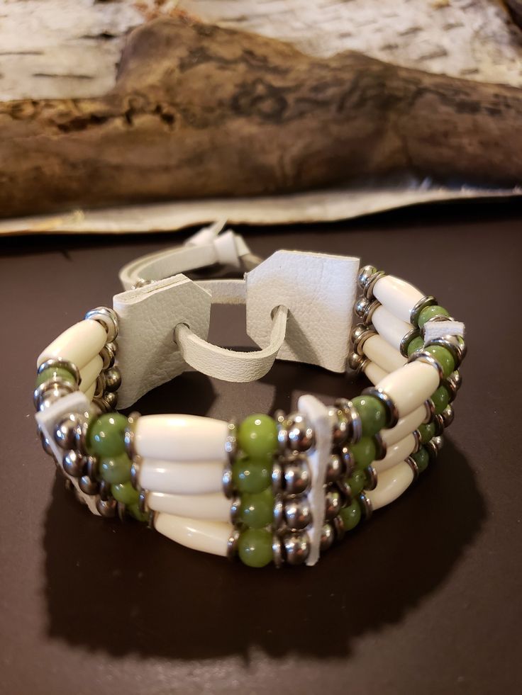 "Canadian Jade Gemstones highlight this four strand bracelet.  Gorgeous white leather with white bone and chrome plated metal beads.  Fully and easily adjustable from about 2\" up to 3\" diameter.  This bracelet will last forever!" Adjustable White Bohemian Cuff Bracelet, Handmade Adjustable White Leather Bracelet, White Handmade Adjustable Leather Bracelet, Handmade White Leather Adjustable Bracelet, Adjustable Handmade White Leather Bracelet, Adjustable Beaded White Cuff Bracelet, Adjustable White Hand-strung Wrap Bracelet, Adjustable Hand-strung White Wrap Bracelet, Adjustable Bone Colored Beaded Jewelry