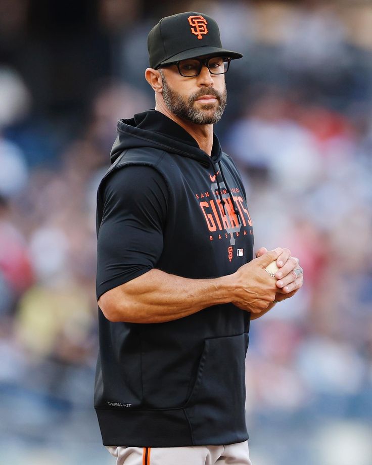 a baseball player wearing a black hoodie and holding his hands together