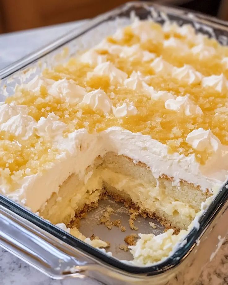 a cake in a glass dish with white frosting and yellow icing on top