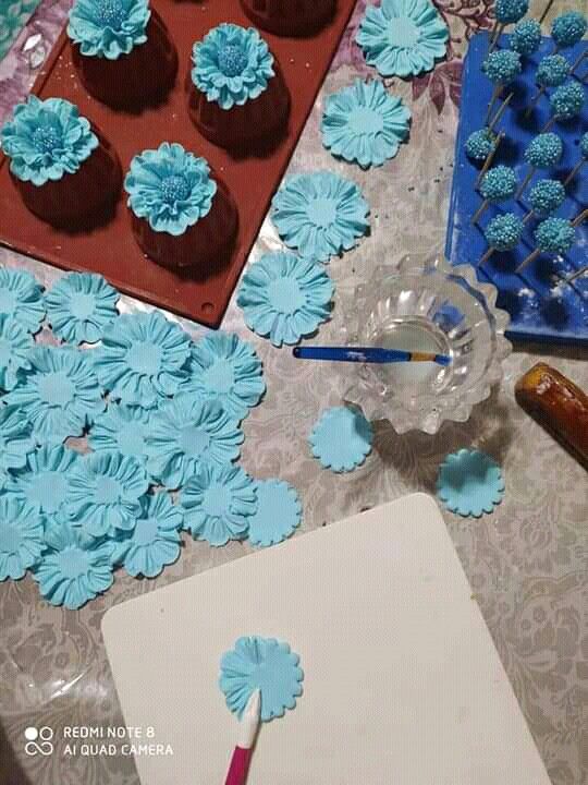 cupcakes with blue frosting are sitting on a table next to a sheet of paper