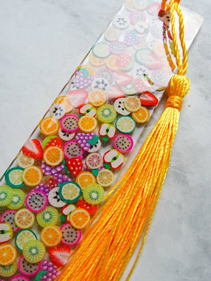 a bookmark with fruit and tassels on it sitting on top of a table