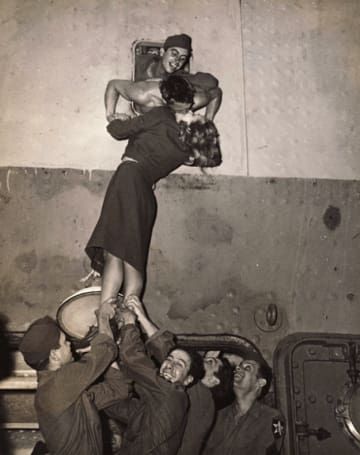 an old black and white photo of people climbing up the side of a building with one woman on her back