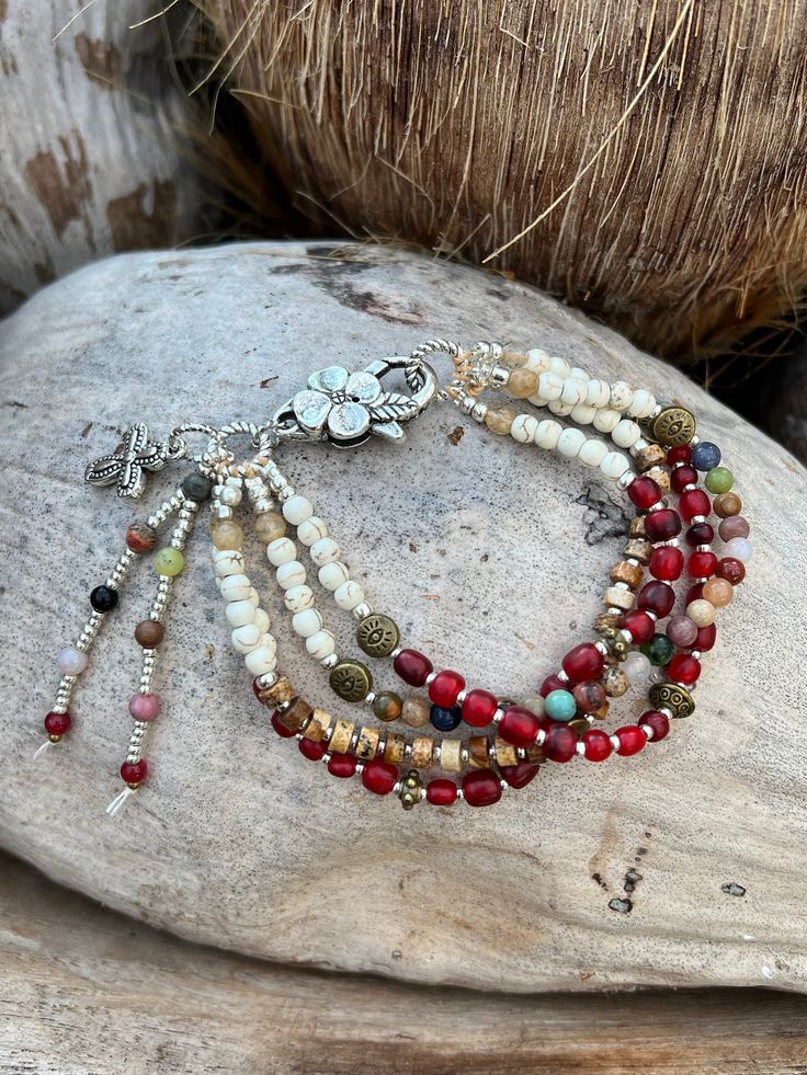 A touch of Africa, all the red beads are handmade in Africa in all sizes and shapes, gemstones right throughout and white howlite stones, brass evil eye beads, with jasper gemstones, attached with a silver flower clasp. 4 stands of beautiful colours.  7.8 inches long White Hippie Bracelet Jewelry, Bohemian Red Beaded Bracelets With Spacer Beads, Bohemian Red Beaded Bracelet With Spacer Beads, Red Hippie Beaded Bracelets For Gift, Hippie Style Red Jewelry For Gift, Artisan Red Beaded Bracelets With Round Beads, Red Bohemian Beaded Bracelets With Natural Stones, Hippie Red Beaded Bracelet Gift, Hippie Style Red Jewelry With Colorful Beads