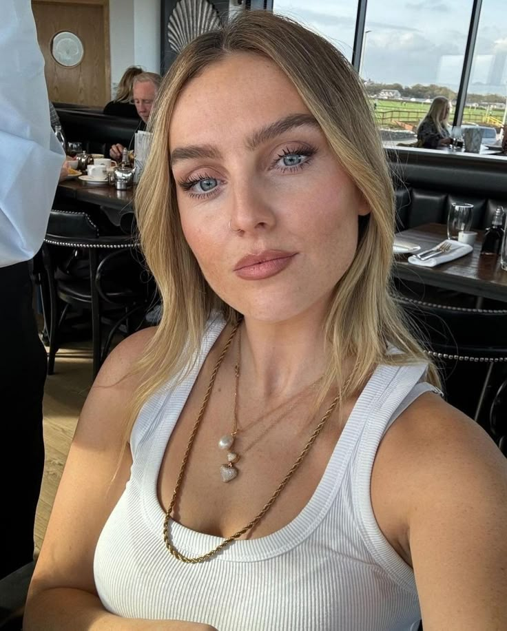 a woman sitting at a table with a plate of food in front of her and looking into the camera