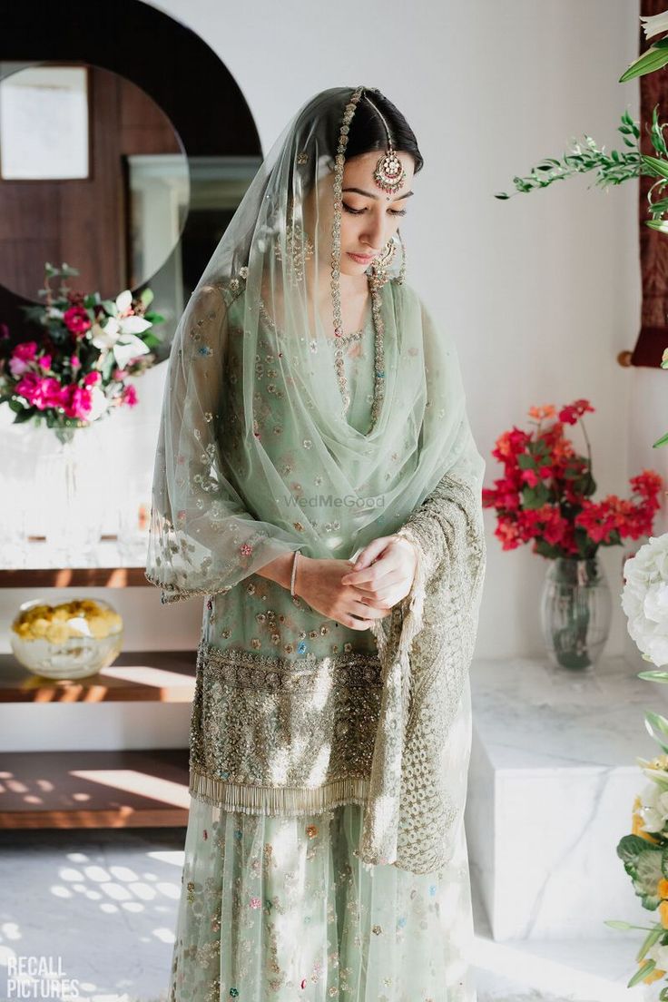 a woman standing in front of flowers wearing a veil