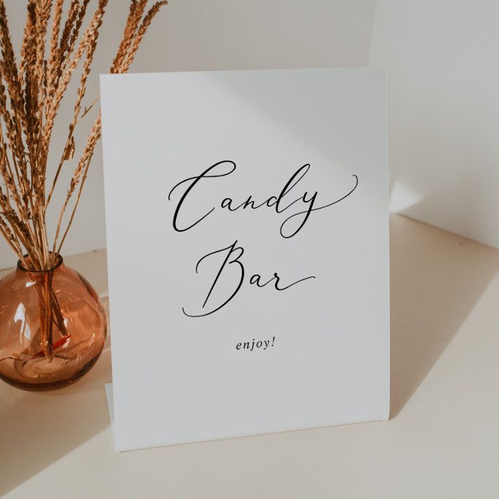 a card that says candy bar on it next to a vase with dry grass in it