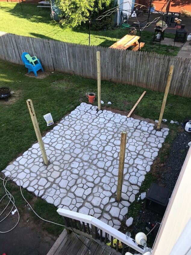 an outdoor area made out of stones and wood sticks with grass in the background, next to a fence