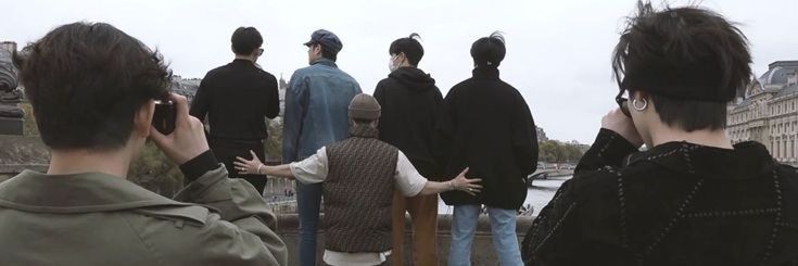 a group of people standing next to each other on top of a bridge over water