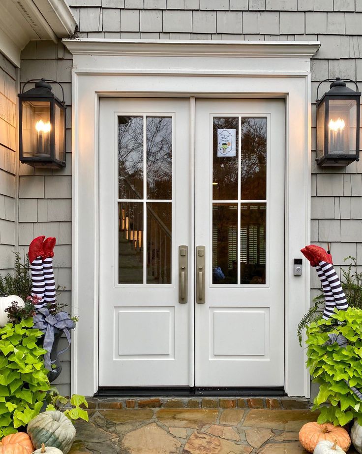 the front door is decorated for halloween with pumpkins and striped sock hats on it