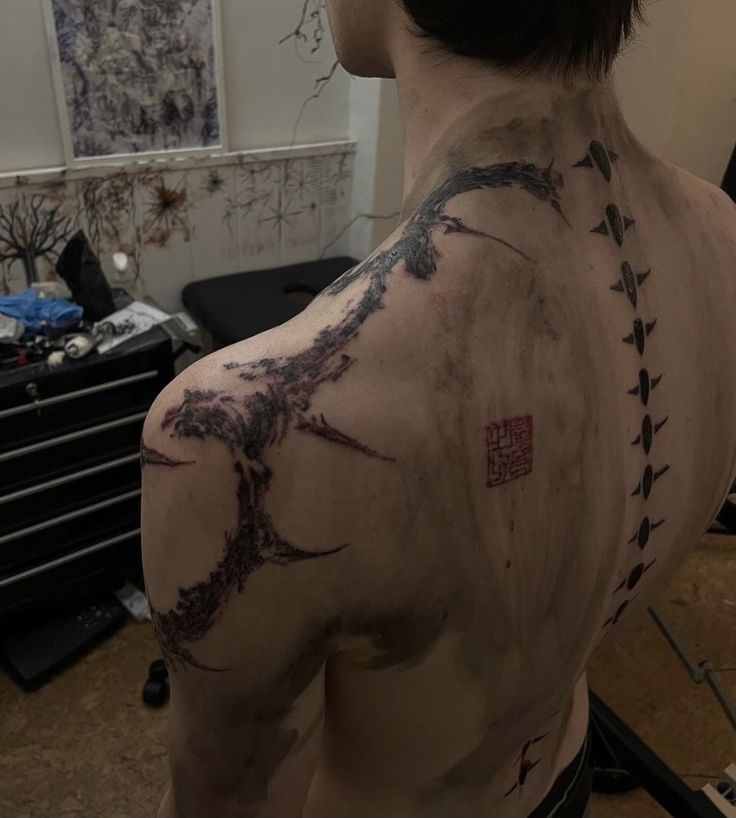 the back of a man's shoulder with tattoos on it and arrows drawn across his chest