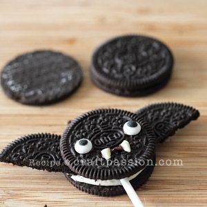 an oreo cookie with eyes and mouth is on a wooden table next to some marshmallows