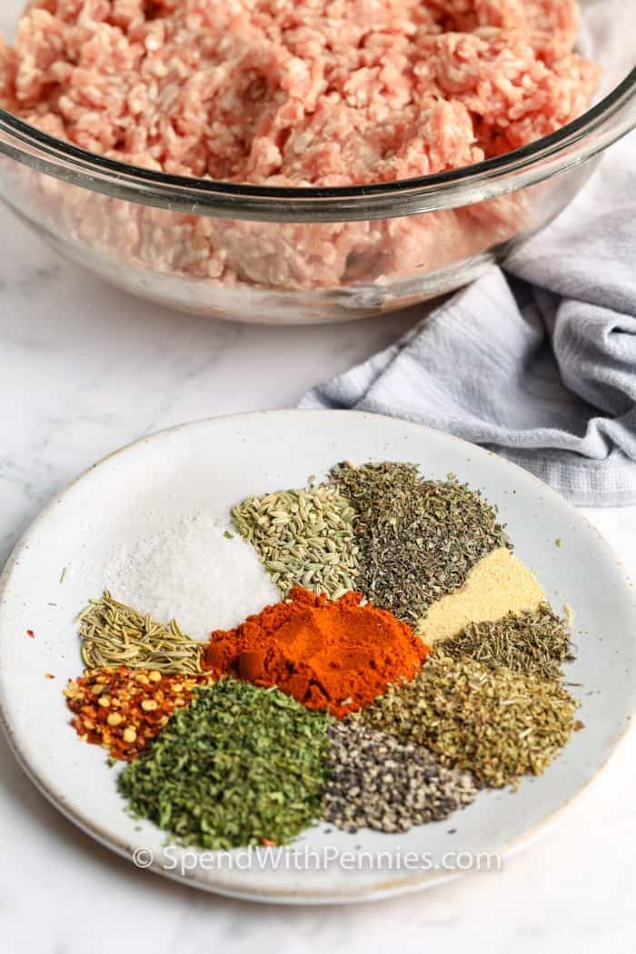 spices and seasonings on a white plate next to a bowl of ground beef meat