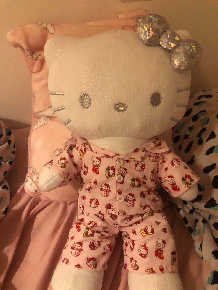 a hello kitty stuffed animal laying on top of a pink bed spread with polka dots