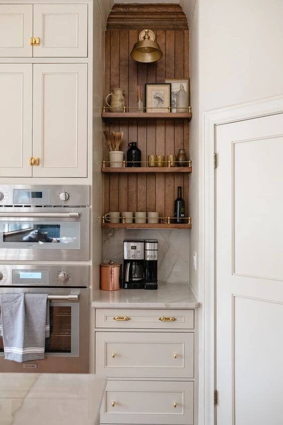 a kitchen with white cabinets and gold knobs on the oven, shelves above it