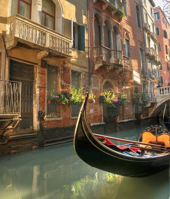 a gondola in the middle of a canal with buildings and flowers on either side