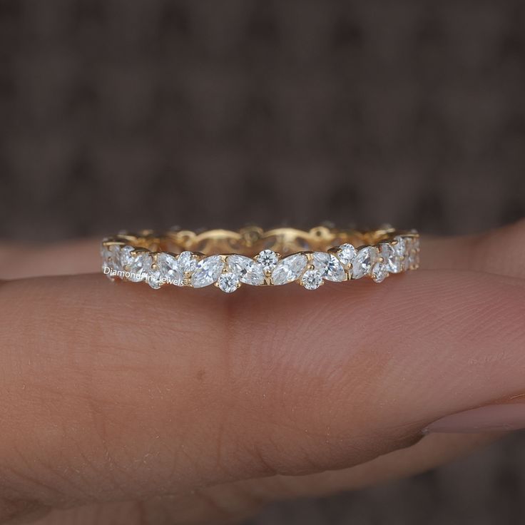 a person's hand holding a gold and diamond wedding band