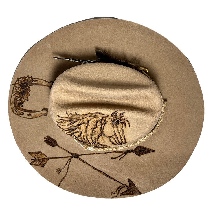 Cowboy hat custom burned by hand specifically for Bourbon Cowgirlby KC Lids. These hats are exclusive and only found here. We worked with the designer to create our very own look. 100% wool hat. One size fits all, as the interior band is adjustable to fit most. A beautiful cattleman rancher style, this distressed almond / beige colored hat is sanded and torched to a beautifully burnished and distressed finish. Firm shape (do not crush). Our artisan has hand burned a beautiful horse with flowing Burnt Cowgirl Hat, Cowgirl Hats Western Brown, Luxury Custom Brown Cowboy Hat, Women’s Felt Cowboy Hat, Brown Brimmed Western Hat, Horse Flowers, Country Music Concerts, Bullet Shell, Pheasant Feathers