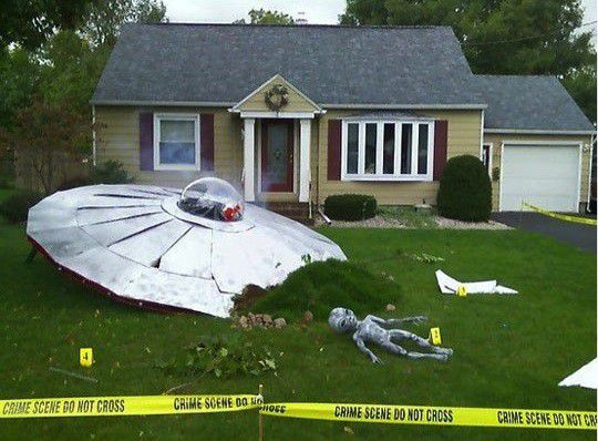 an upside down umbrella laying on the grass in front of a house with caution tape around it